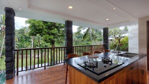 A modern kitchen with a large island, wooden cabinets, and a view of lush greenery. - Kelusa Hill (Payangan)