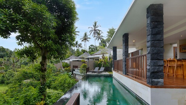 A poolside area with a clear view of the pool, stone pillars, and a bar area with wooden chairs. - Kelusa Hill (Payangan)