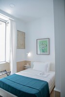 Une chambre d’hôtel avec un lit, une table de chevet, une œuvre d’art florale encadrée et une fenêtre avec des rideaux.