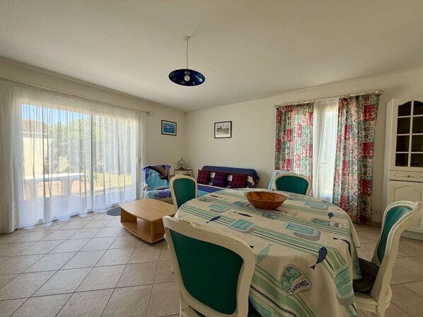 Un coin repas avec une table dressée pour quatre personnes, des chaises, un banc et une vue dégagée grâce à de grandes fenêtres.