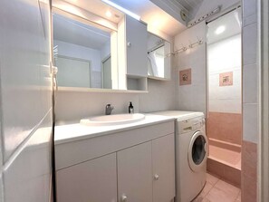 Moderni kylpyhuone, jossa on pesuallas, peili ja pyykinpesukone.