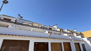 Un immeuble à plusieurs étages, doté d’une façade blanche, d’un socle en pierre et de plusieurs portes de garage.
