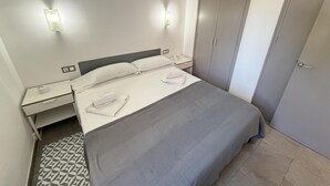 Une chambre d’hôtel avec un lit, des tables de chevet, une armoire et un tapis à motifs.