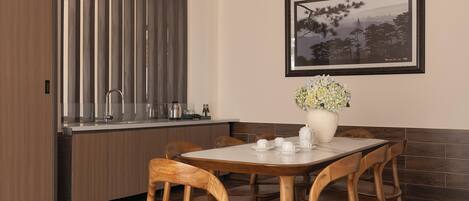 A dining area with a wooden table and chairs, a vase of flowers, and a framed picture on the wall.