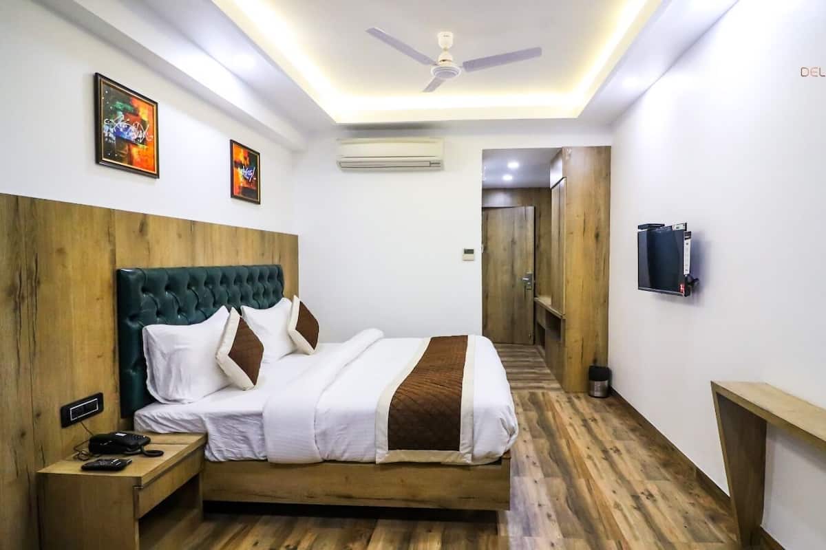 A hotel room with a bed, wooden headboard, bedside table, and a television.