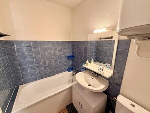 A bathroom with a bathtub, a sink, and a mirror.