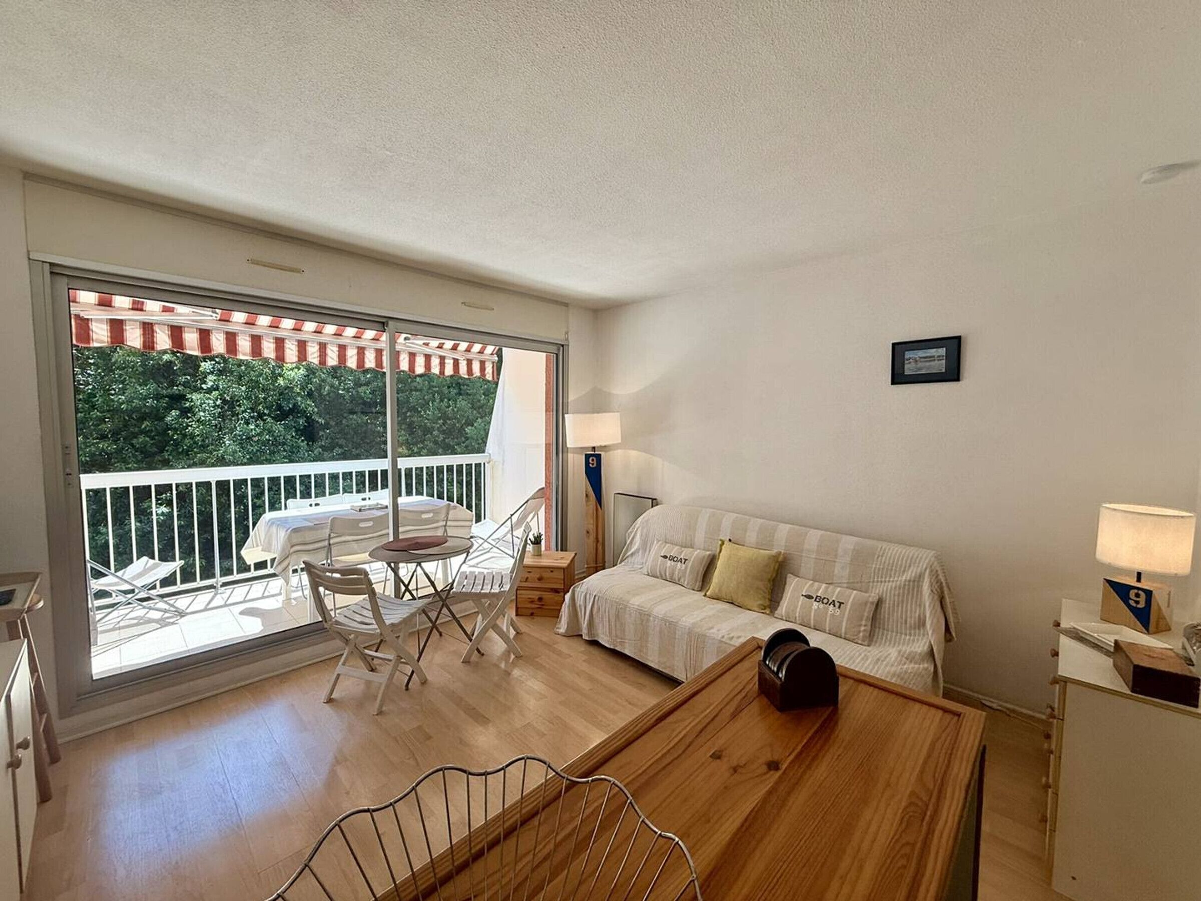 A room with a balcony, a sofa, a table, and a chair.