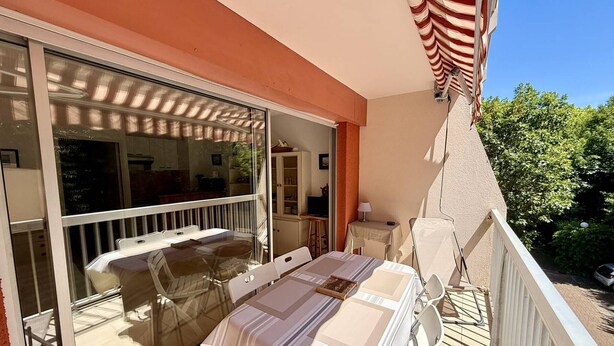 Ein Balkon mit Tisch und Stühlen, eine Schiebetür und Blick ins Freie.