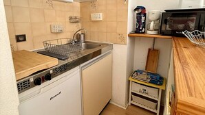 Eine kompakte Küche mit Geschirrspüler, Spüle und Mikrowelle.