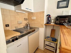 Une cuisine de taille réduite équipée d’un lave-vaisselle, d’un évier et d’un four à micro-ondes.