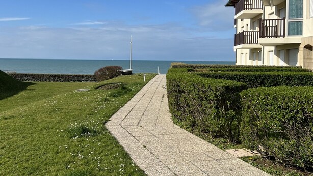 A pathway leading to a building with a view of the sea. - Cabourg: Renovated Duplex 2P, Direct Beach, Fiber (Cabourg)