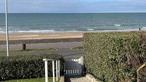 A coastal view with a beach, a road, and a hedge. - Cabourg: Renovated Duplex 2P, Direct Beach, Fiber (Cabourg)