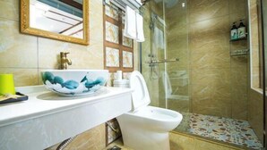 A bathroom with a marble sink, a toilet, a glass shower enclosure, and a mirror with a decorative frame.