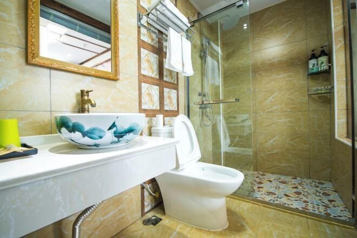 A bathroom with a marble sink, a toilet, and a glass-enclosed shower.