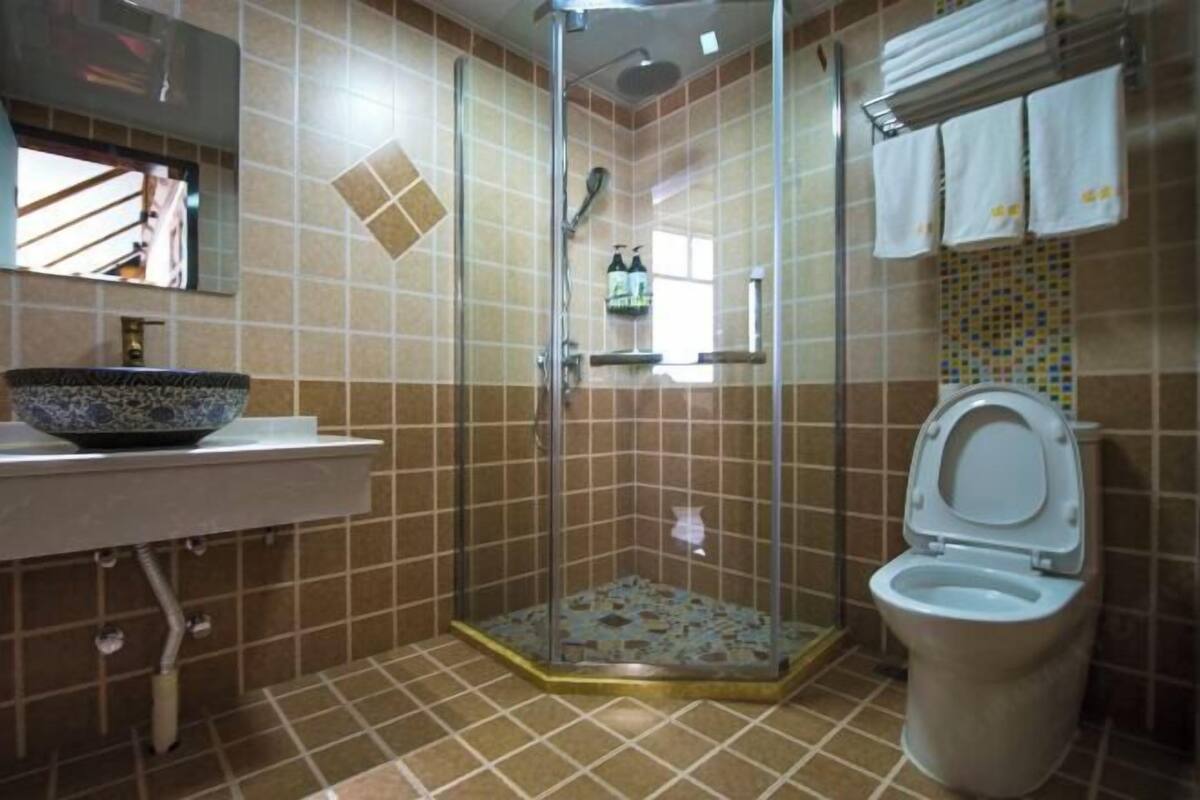 A bathroom with a glass-enclosed shower, a toilet, and a sink with a decorative bowl.