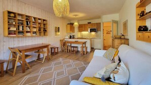 A cozy living room with a sofa, a dining table, and a kitchen area with wooden cabinets and a microwave. - Spacious apartment in the heart of Les Orres 1650, 3 bedrooms, sleeps 6/8 (Les Orres)