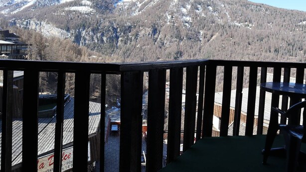 A mountain view from a balcony with a wooden railing, a table, and chairs. - Spacious apartment in the heart of Les Orres 1650, 3 bedrooms, sleeps 6/8 (Les Orres)