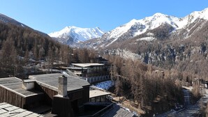 A mountain lodge with a wooden exterior, large windows, and a view of snow-capped mountains. - Spacious apartment in the heart of Les Orres 1650, 3 bedrooms, sleeps 6/8 (Les Orres)