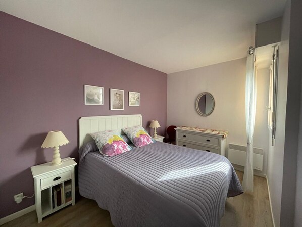 A bedroom with a bed, nightstands, a dresser, and a mirror.