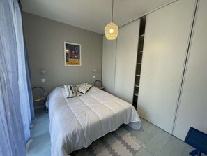 Quarto com cama, luminária pendente, quadro na parede e armário.