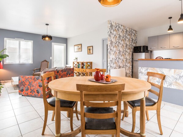 A modern kitchen with a central island, wooden chairs, and a dining table.