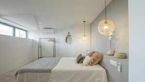 A modern bedroom with a bed, bedside lamps, a wardrobe, and a large window.