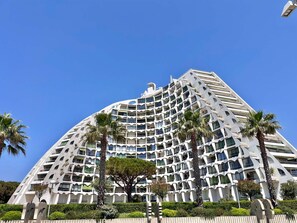 Un hôtel moderne à l’architecture originale, caractérisée par des courbes, doté de nombreux balcons et agrémenté de palmiers au premier plan.