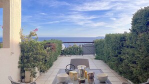 A patio with outdoor furniture, a table set with various items, and a view of the sea. - Quiet apartment with pool and parking, near beach, for 4 people in Rayol-Canadel (Rayol-Canadel-sur-Mer)