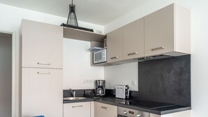 Una cocina moderna con microondas, cafetera y horno. Hay una mesa de comedor con sillas.