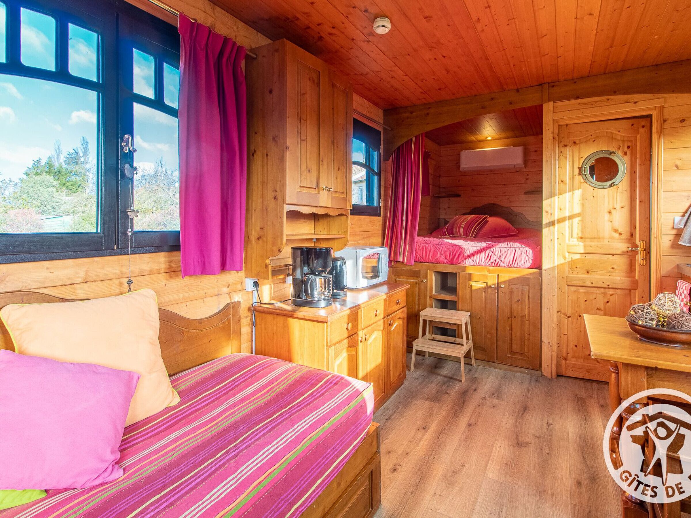 Un intérieur de chalet chaleureux avec un lit, une kitchenette et un petit coin repas.