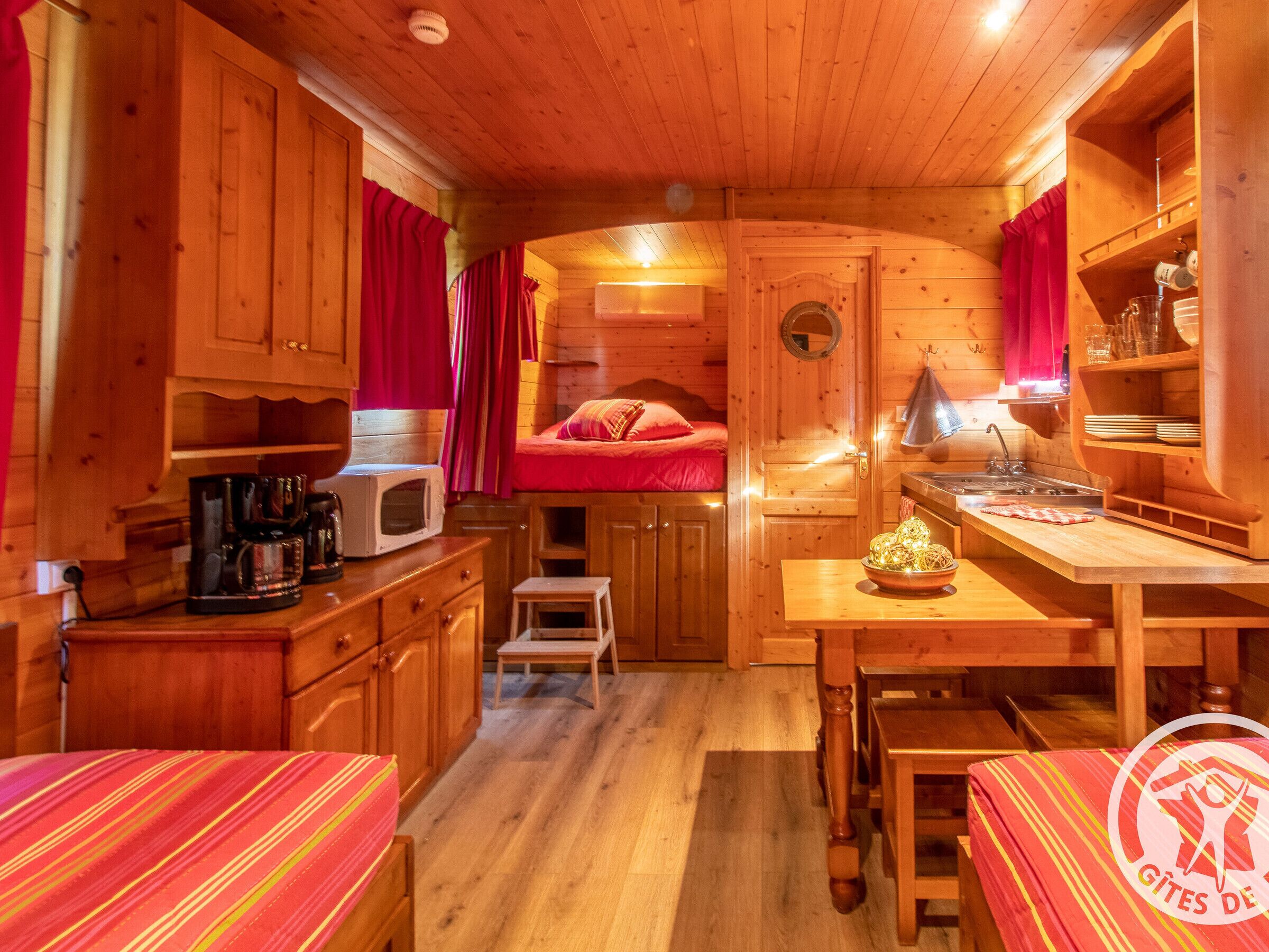 A cozy cabin interior with a kitchenette, a bed, and a dining area.