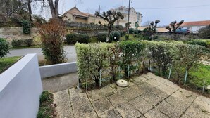 Un quartier résidentiel avec une cour dallée, un mur blanc et, au fond, un bâtiment dont le toit est recouvert de tuiles.