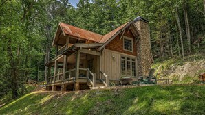 A cabin with a stone chimney, wooden exterior, and a porch with a railing. - Cider Mill House overlooking private stream w/ firepit (Ellijay)