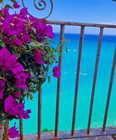 Varanda com grade de metal e vista para o mar azul-turquesa.