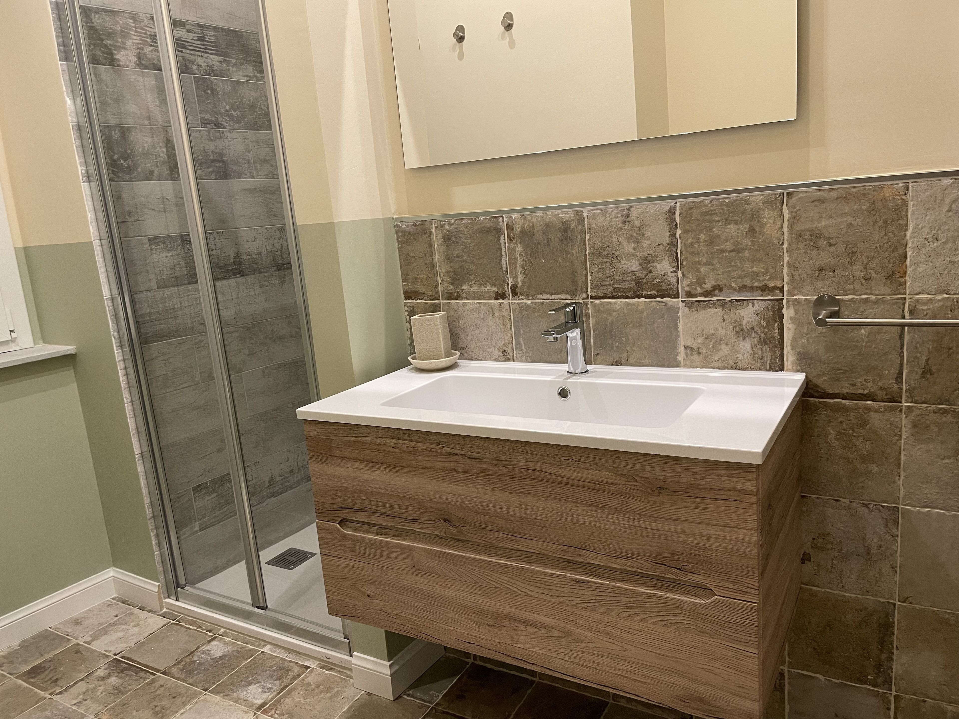 Un baño con ducha, lavabo y tocador de madera.