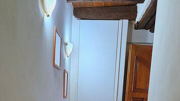 A hallway with a tiled floor, a wooden door, and a vase with branches.