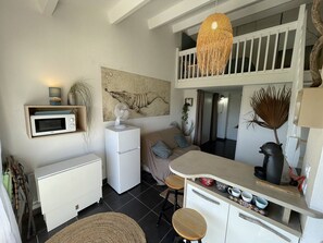 Cozinha compacta com micro-ondas, geladeira e área de refeições com banquetas.