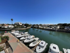 Uma marina com vários barcos atracados, céu azul límpido e edifícios ao fundo.
