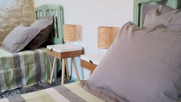 Una habitación con dos camas, una mesita y dos lámparas.