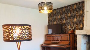 Un salon comprenant un canapé, une lampe sur pied, un piano, une télévision et une cheminée.