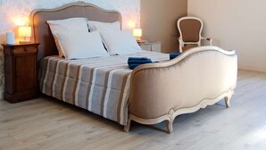 Une chambre avec un grand lit, deux tables de chevet, une chaise et un mur décoré d’un motif.