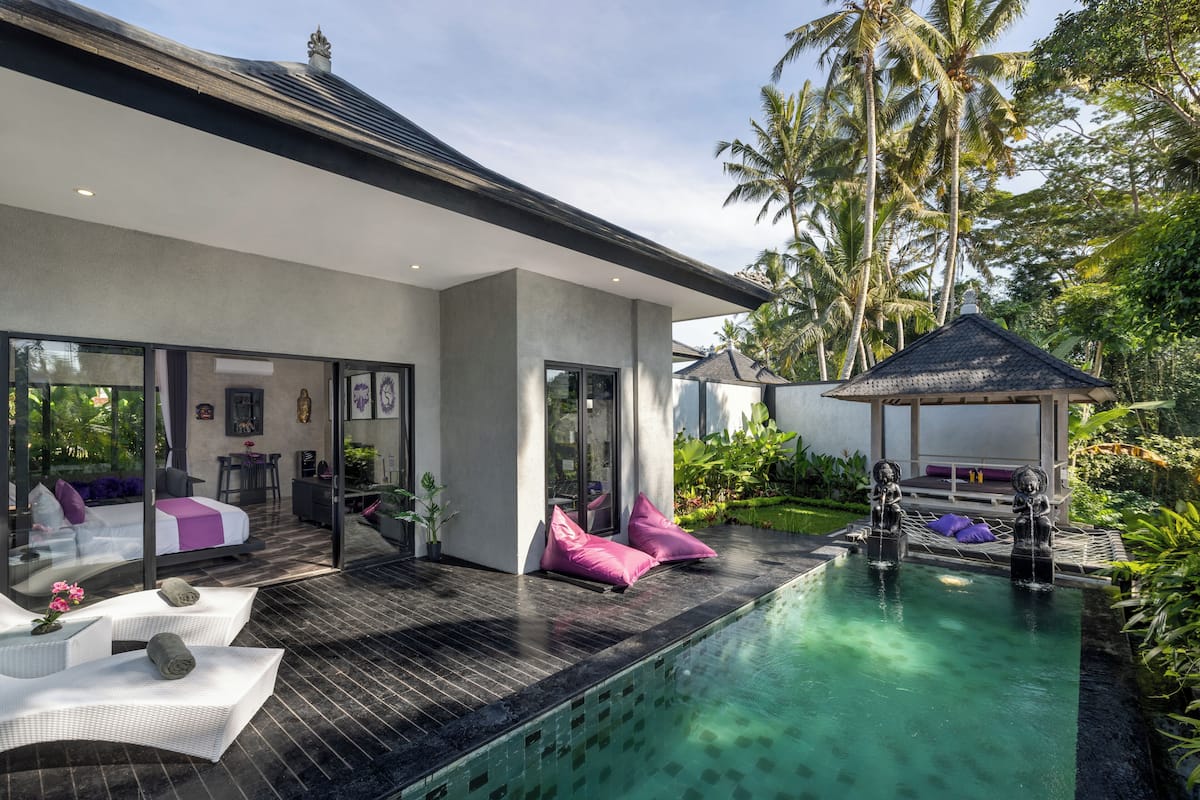 A modern house with a swimming pool, outdoor seating, and a covered area with cushions.