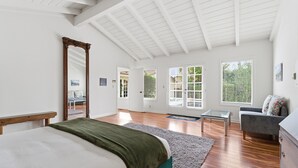 A spacious bedroom with a large bed, a wooden bench, a glass table, a gray sofa, and a dresser. - Pool, Foosball, Pool Table, Basketball Family Friendly, blocks from the beach! (San Diego)