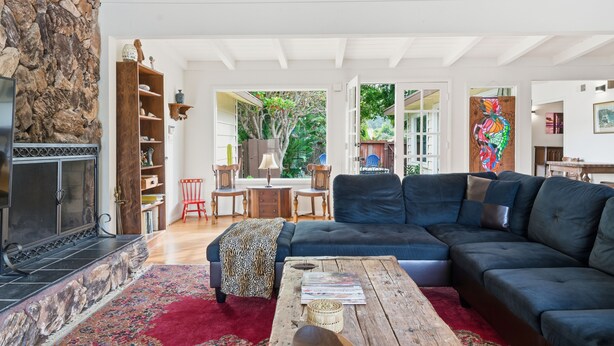 A spacious living room with a stone fireplace, a dark blue sofa, a wooden coffee table, and a red rug. - Pool, Foosball, Pool Table, Basketball Family Friendly, blocks from the beach! (San Diego)