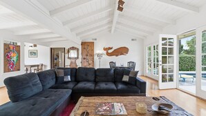 A spacious living room with a dark sectional sofa, a wooden coffee table, and a large whale mural on the wall. - Pool, Foosball, Pool Table, Basketball Family Friendly, blocks from the beach! (San Diego)