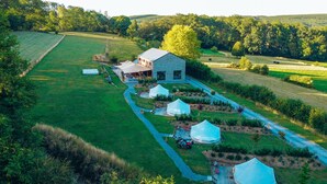 Un chalet rustique avec un bâtiment en pierre, plusieurs tentes et un jardin bien entretenu.