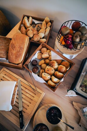 Une table en bois sur laquelle sont disposés divers produits de boulangerie et des fruits.