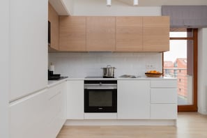 Una cocina moderna con armarios blancos, horno empotrado y ventana con vistas a edificios.