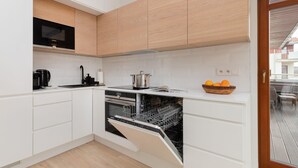 Una cocina moderna con armarios blancos, un microondas integrado y un lavavajillas.