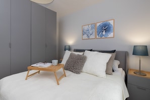 Un dormitorio con cama, mesitas de noche, armario y obras de arte en la pared.